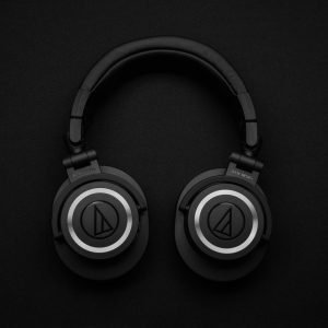 Close-up of black over-ear headphones on a black background, showcasing modern design.