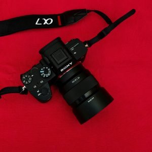 Top view of a DSLR camera against a bold red backdrop, showcasing professional photography equipment.