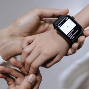 Close-up of a mother assisting her daughter with a smartwatch, emphasizing family care and technology.